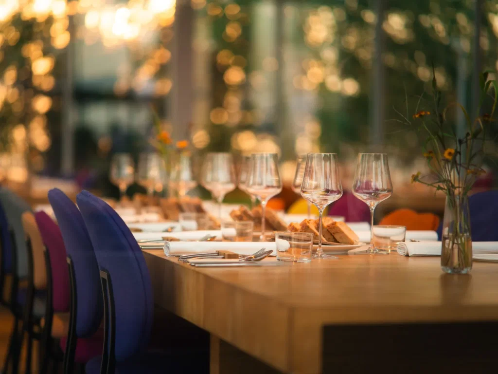Lange gedekte tafel met wijnglazen in een restaurant met warm licht, gefotografeerd door Dies