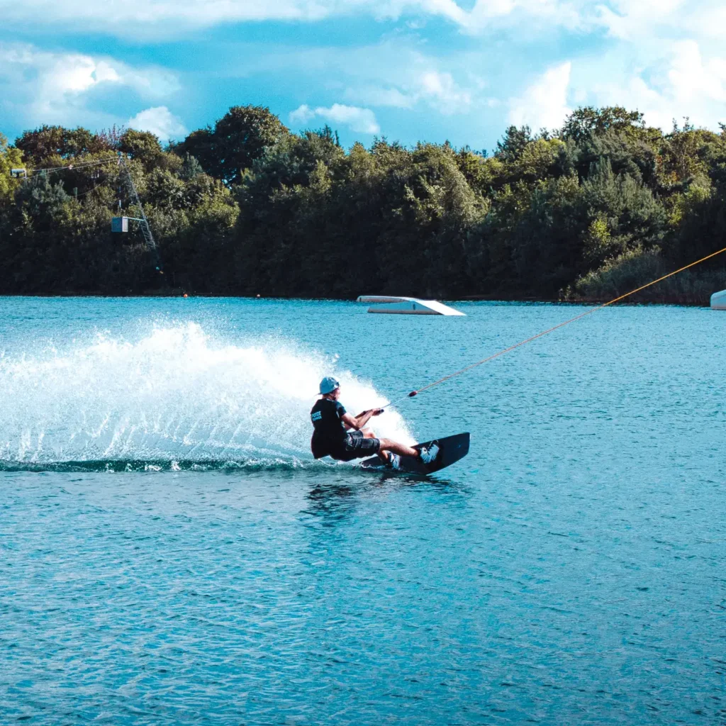 Wakeboarder trekt een boog over blauw water, gefotografeerd door Dies